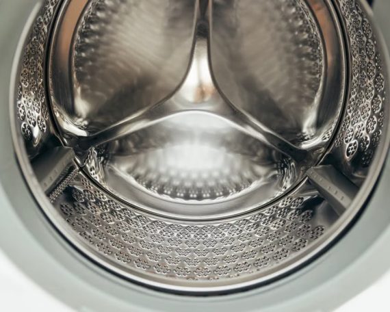 Detailed view of a clean, modern washing machine drum, showcasing shiny stainless steel interior.