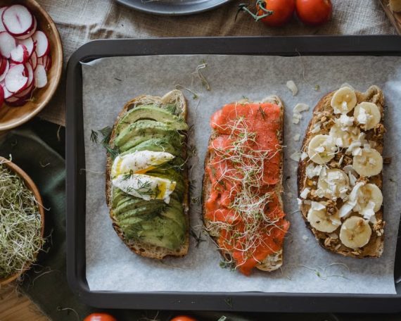 Tray of three assorted open-faced sandwiches with fresh toppings for a delicious meal.